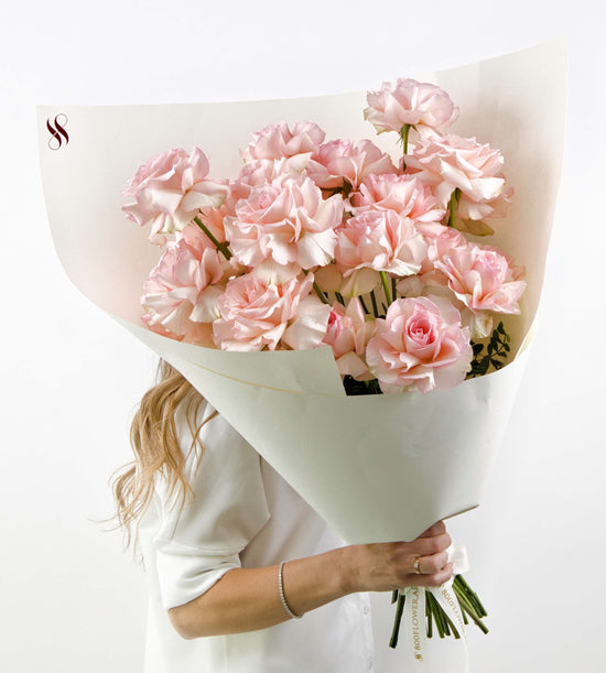 Soft pink roses with ruffled edges arranged in an elegant bouquet.