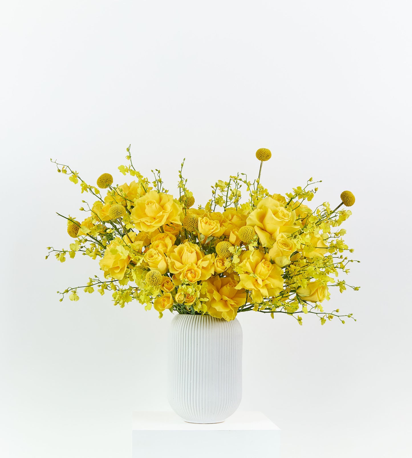 Yellow roses in a white ribbed vase, radiating joy and warmth.