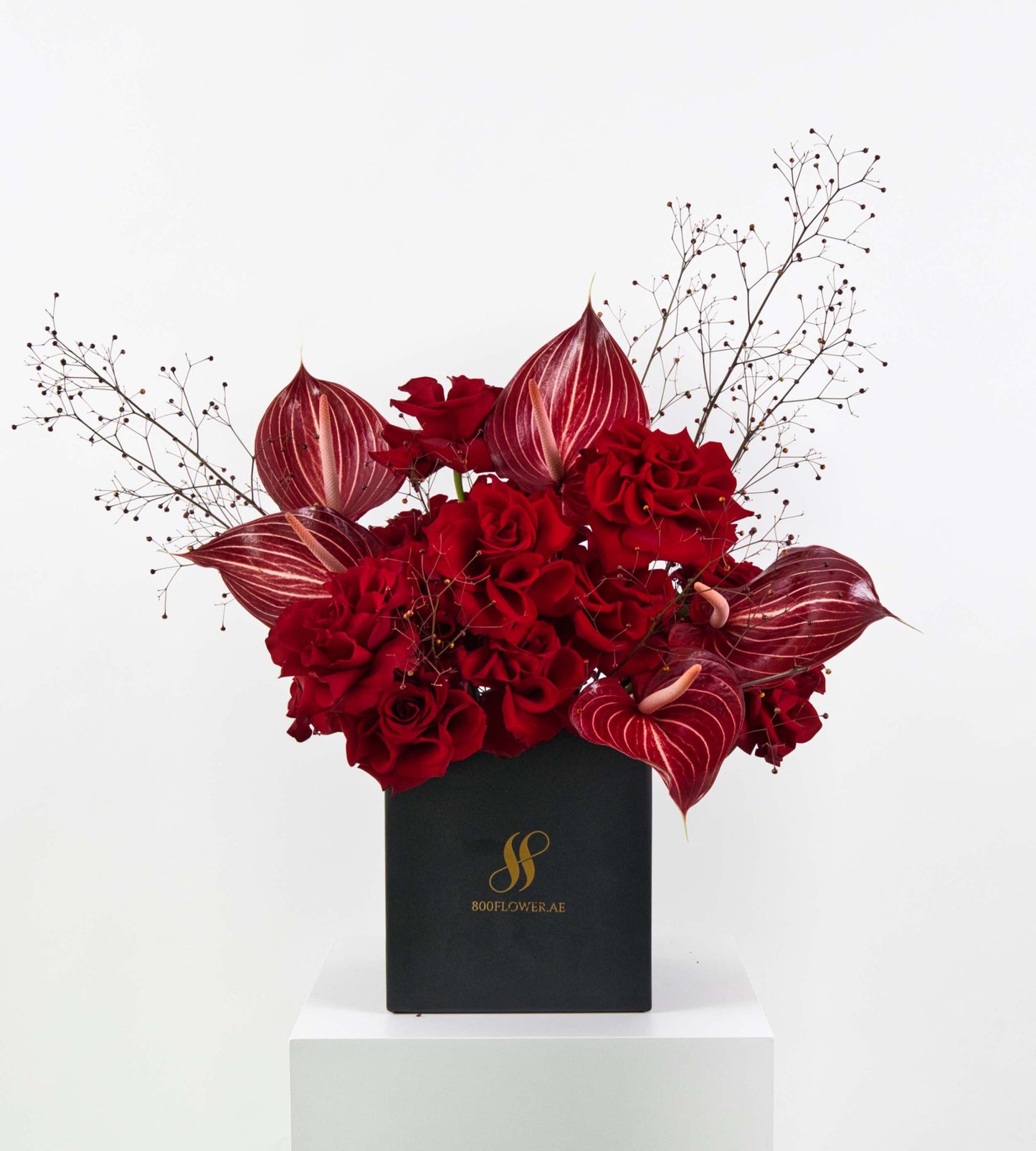 Bouquet of red roses and striped anthuriums with wild foliage.