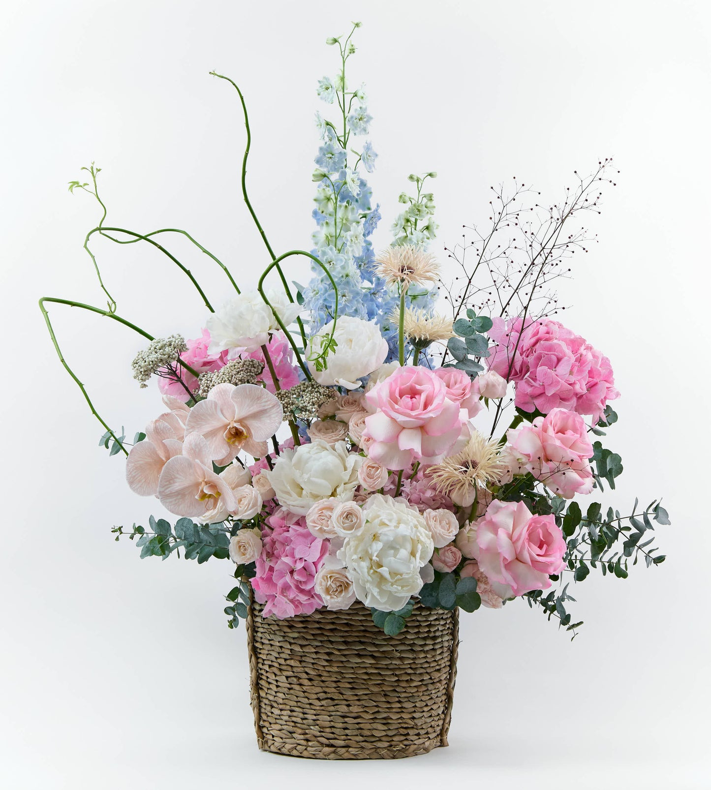 Basket floral arrangement with blush flowers and soft textures, inspired by a spring garden at golden hour.