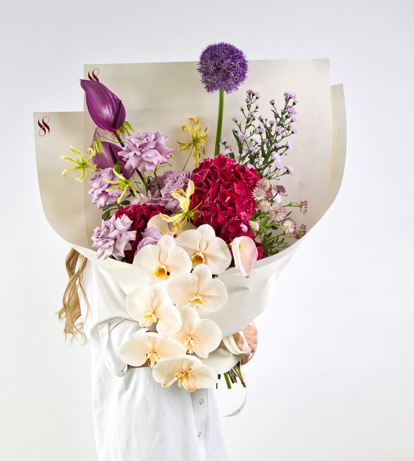 bouquet featuring orchids, anthuriums, proteas, and exotic foliage in a dramatic arrangement.