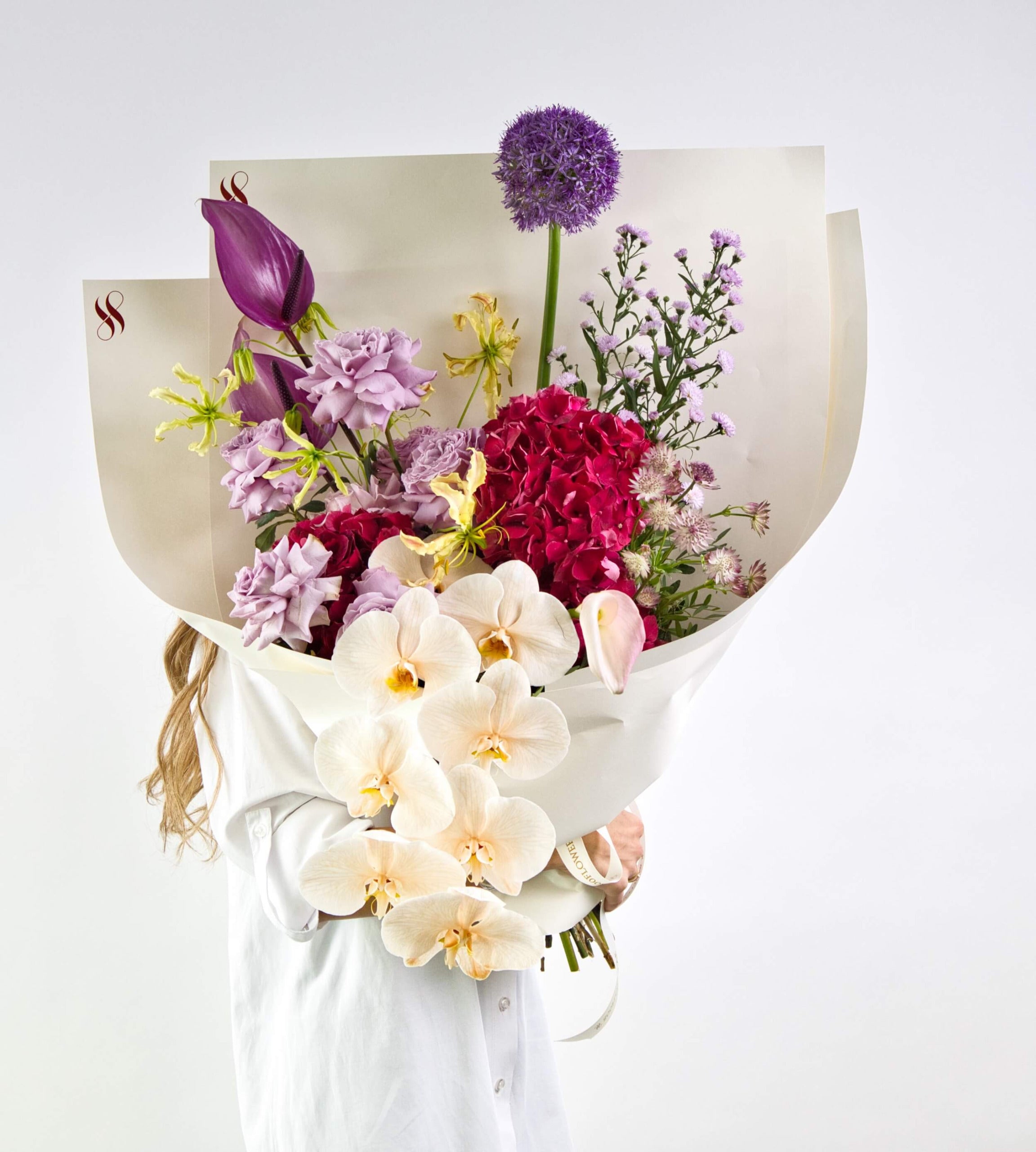 bouquet featuring orchids, anthuriums, proteas, and exotic foliage in a dramatic arrangement.