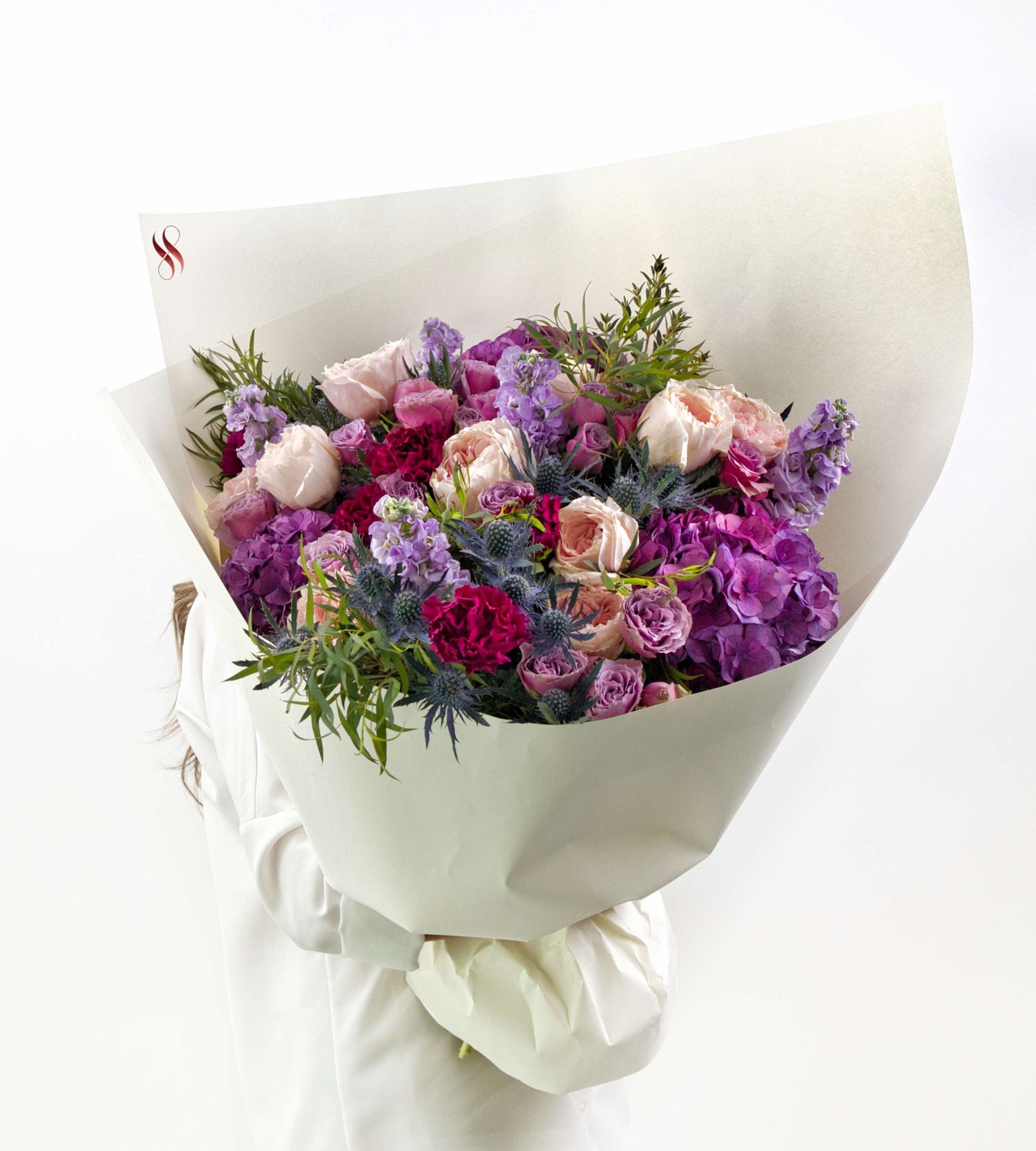 Elegant floral bouquet in blush, violet, and wine tones with soft greenery.