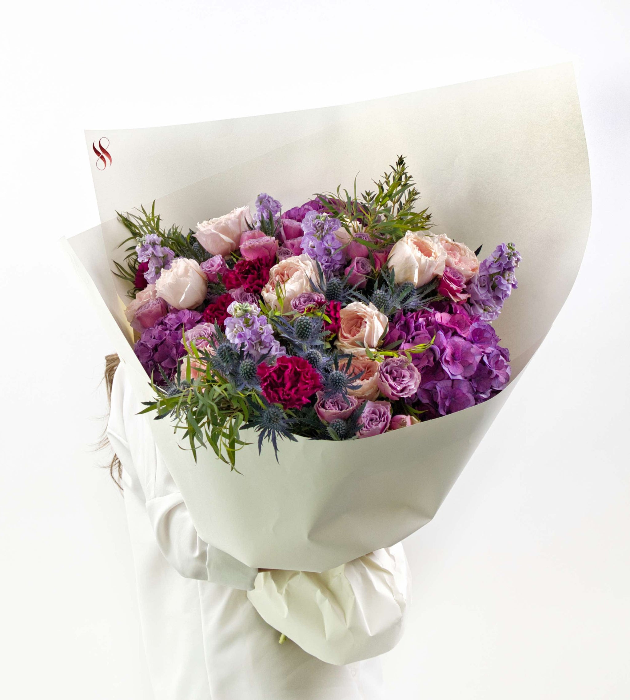 Elegant floral bouquet in blush, violet, and wine tones with soft greenery.