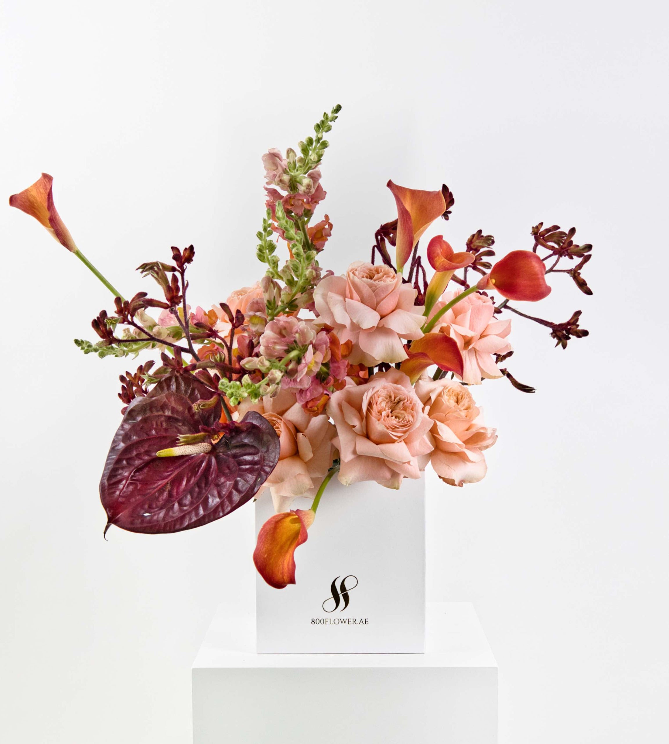 Bouquet with peach roses, burnt orange calla lilies, and burgundy anthuriums.