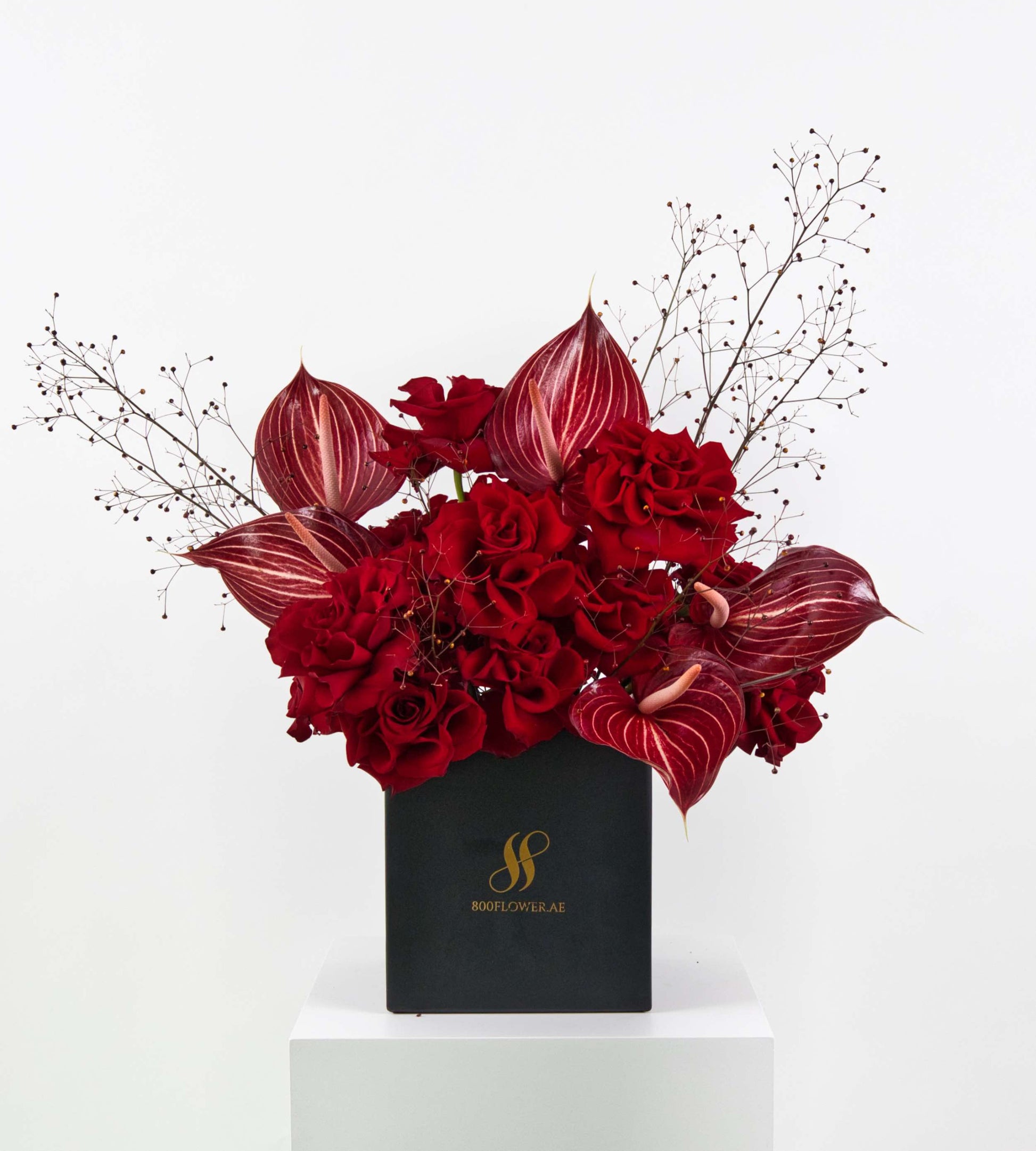 Bouquet of red roses and striped anthuriums with wild foliage.